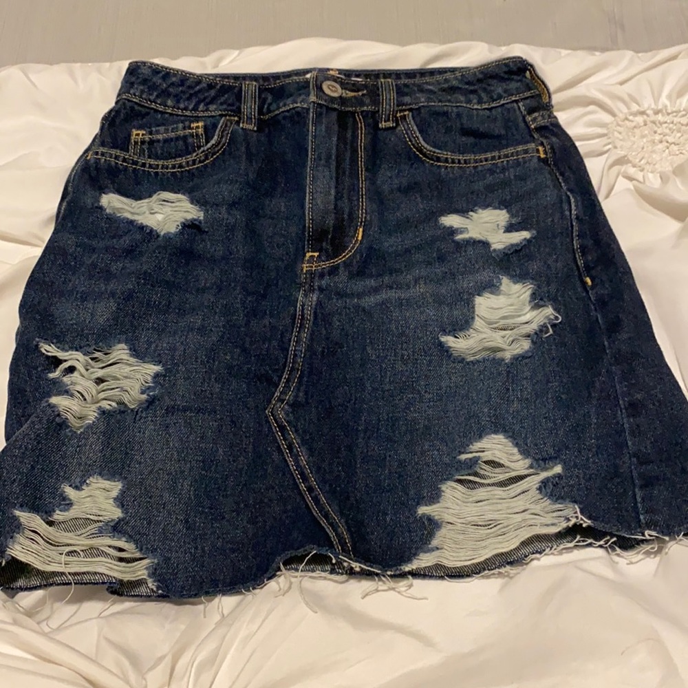 Dark colored denim skirt with rips in the front